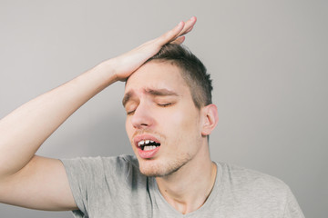 Fototapeta premium The young guy on a light background depicts different emotions