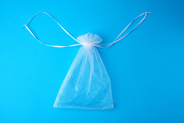 bag made of white transparent synthetic fabric for gifts and cosmetics on a blue background