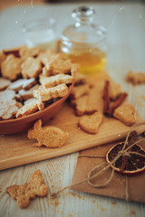 cookies lies in a plate on a wooden board, next to a jar of honey and a letter with dried orange