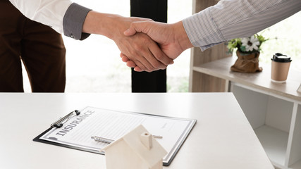 Agent and customer are shaking hand after finishing an advice for taking the house insurance