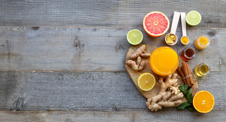 Fototapeta na wymiar Top view on the immune system booster - orange juice, ginger, turmeric, citruses, and honey on the old wooden table