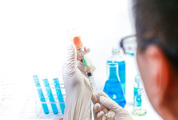 Medical or scientific researcher or man doctor looking at a test tube of clear solution in a laboratory