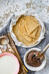 Baked crispy tasty crepes or thin pancakes and crepes dough. Ingredients on table. Vegan dessert. Homemade chocolate paste spread.