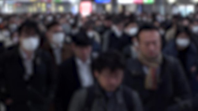 TOKYO, JAPAN - MARCH 2020 : Crowd of people walking at morning rush hour. Commuters going to work. People wearing mask to protect from Coronavirus(COVID-19). Blurred slow motion shot.