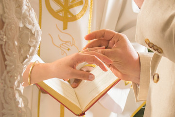 groom putting ring on bride during religious ceremony