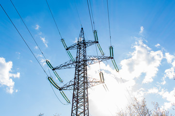 High voltage power pylons against a blue sky with clouds