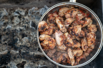 Picture of a kebabs in a large pan are in an extinct brazier