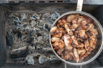 Picture of a kebabs in a large pan are in an extinct brazier