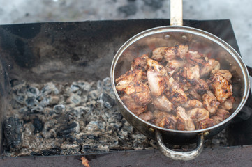 Picture of a kebabs in a large pan are in an extinct brazier