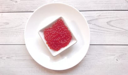 Red caviar of salmon fish on a white plate.