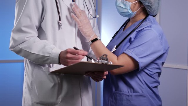 Registered Nurse(RN) in blue scrubs, scrub cap, and a protective face mask seducing a  Medical Doctor (MD ) in a lab coat with a stethoscope by pulling on his tie and whispering into his ear at their 