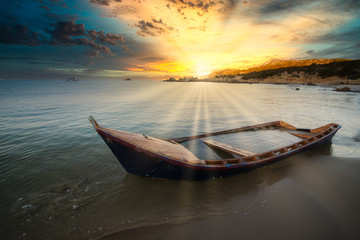 Wooden boat wrecked on a sandy beach.