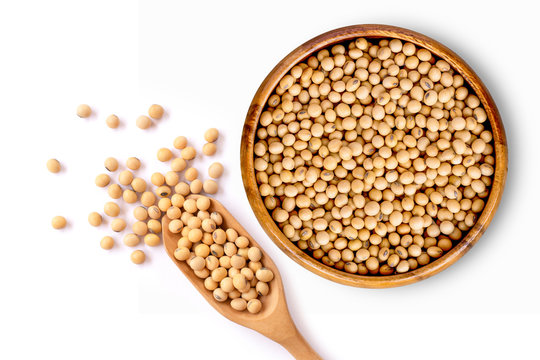 Closeup soy beans in wooden bowl and scoop isolated on white background. Overhead view. Flat lay.