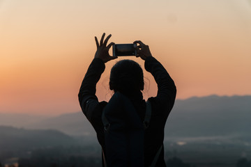 Fototapeta premium silhouette of a man making a photo at sunset