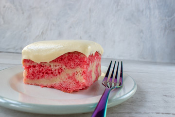 Slice of yellow jello cake with pudding frosting on plate with fork