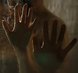 Hands of man and woman on wet glass in the shower.