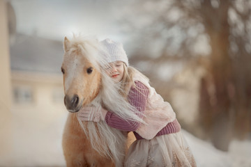 Little girl with palomino miniature horse in winter park - obrazy, fototapety, plakaty