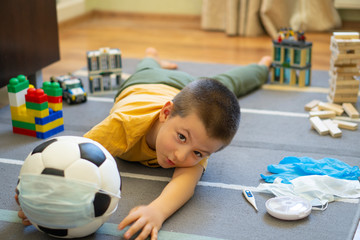 Fototapeta premium Soccer ball in a medical mask. Activities at home with your children during home coronavirus quarantine.Sports at home. Stay at home