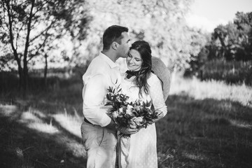 stylish groom and happy bride hugging under retro bulbs lights in wooden barn. rustic wedding concept, space for text. newlyweds couple embracing, sensual romantic moment