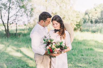 Naklejka premium Happy bride and groom posing in the woods against the backdrop of a wooden cottage. Wedding in a vintage Boho style.