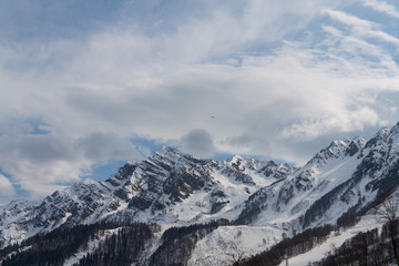 Peaks of snow-capped mountains against the blue sky with clouds