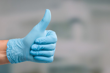 close up of a hand in medical gloves showing thumbs up
