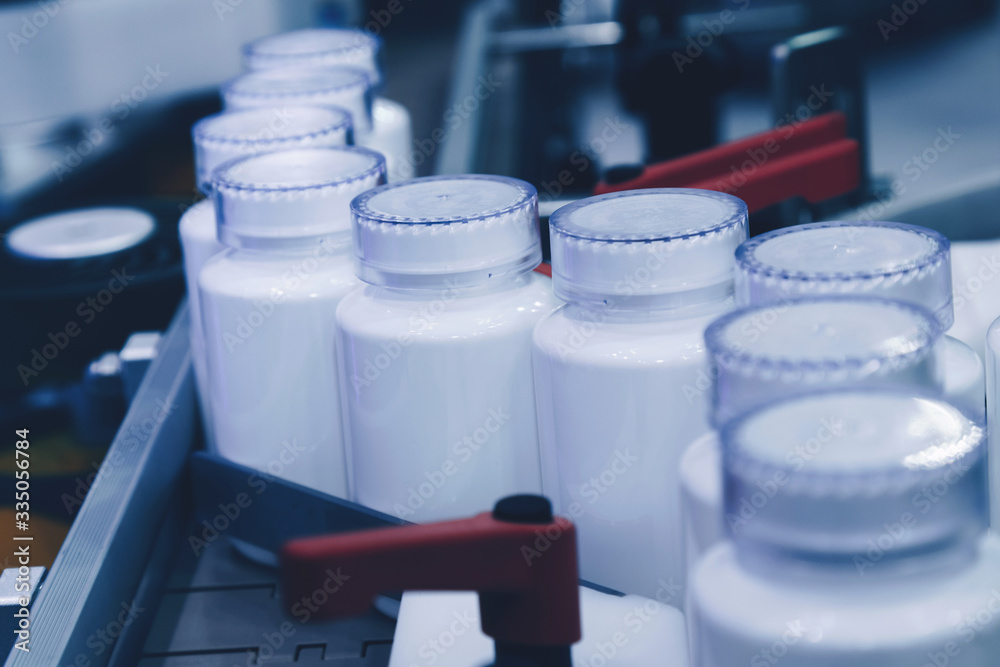 Wall mural white plastic bottle on the production line of the conveyor at filling machine in the medical factor