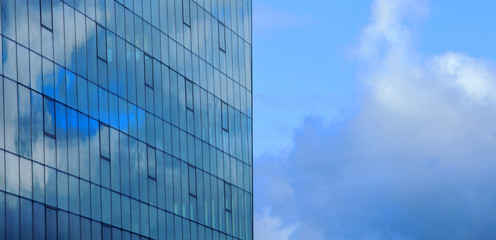 Fototapeta premium Fragment of the facade of a glass building against the sky with reflection of clouds