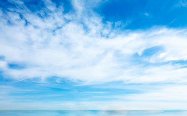 Full frame of blue sky with clouds and skyline above the water
