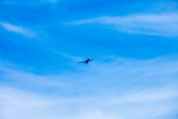 A plane against a blue sky with beautiful clouds comes in to land