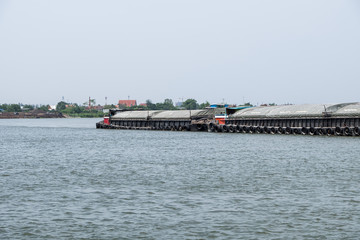 The large cargo boat is loading the sand  in the large river.