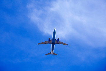 Airplane close-up on a background of blue sky with cirrostratus clouds. Bottom view