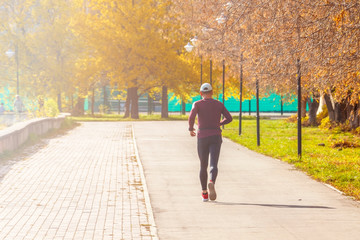 A man runs through the park on an autumn sunny day