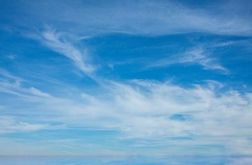 Sky with cirrostratus clouds above the horizon with a thin strip of sea