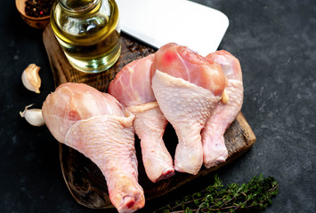 raw chicken legs with spices and meat knife on a stone background