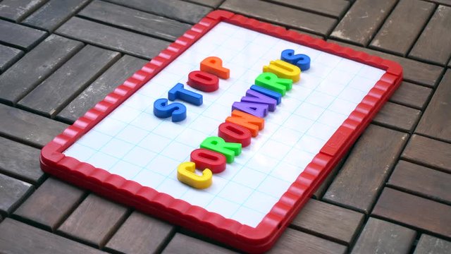 Europe, Italy , Milan - life stile during n-cov19 Coronavirus outbreak epidemic - children boy five years old play with colored letters and write stop Coronavirus on a magnetic board 