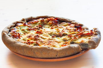 Quiche of artichoke and ham on ceramic plate on light wooden background. Horizontal view. Copy space.