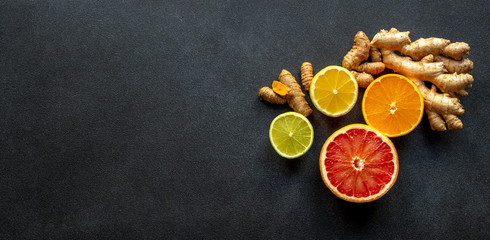 Top view on healthy ingredients for boosting immunity - ginger, turmeric, and citruses on the black backboard