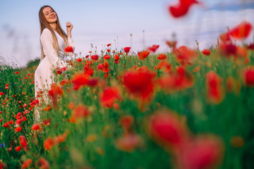 beautiful red poppies in a field with tall grass. girl posing in