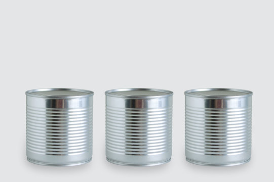 Three cans of canned food in metal can on a gray background.