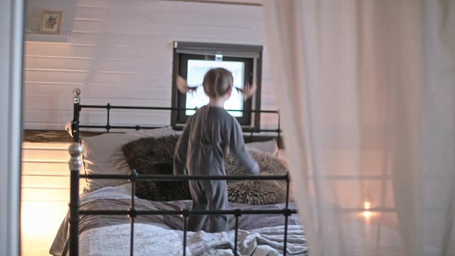 Little cute girl jumping on the bed. A girl in pajamas is freaking out in the bedroom.
