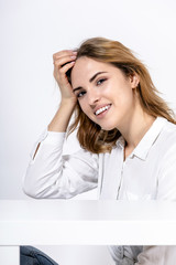 portrait of a young happy smiling girl in a white shirt on a white background