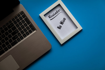 Work from home concept with Reminder Be Nice framed text with laptop flat lay