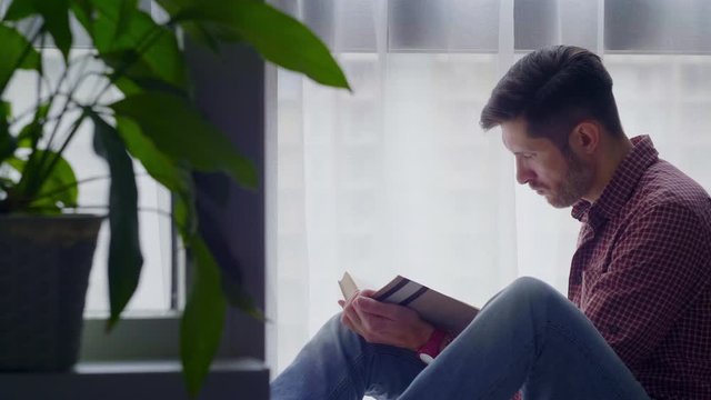A man reads a book sitting by the window.4