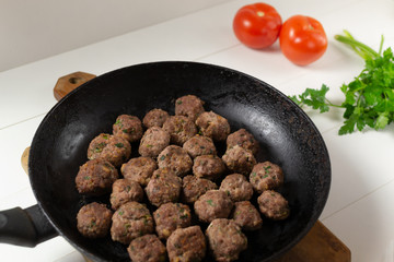 Homemade fried meatballs with herbs in a pan on a white background. Swedish traditional cuisine.