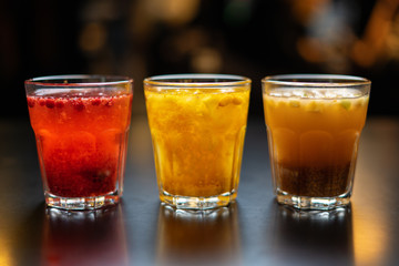 Hot drinks from fruits and berries on a black table against the background of the cafe's interior. Close up.