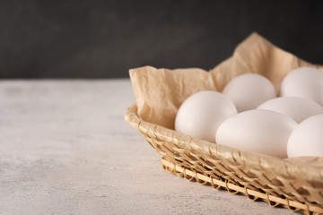 Eggs in a square wicker basket on parchment paper. Close-up, copy space.