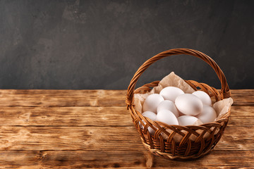 Farm eggs in a wicker basket on a wooden table. Copy space.