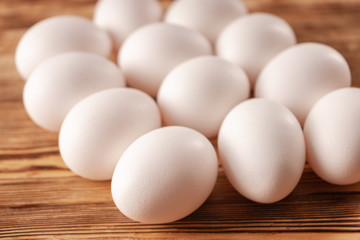 White eggs on a wooden plank table. Close up.