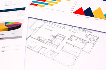 Architects work at a desk on plans and financial documents of their buildings.